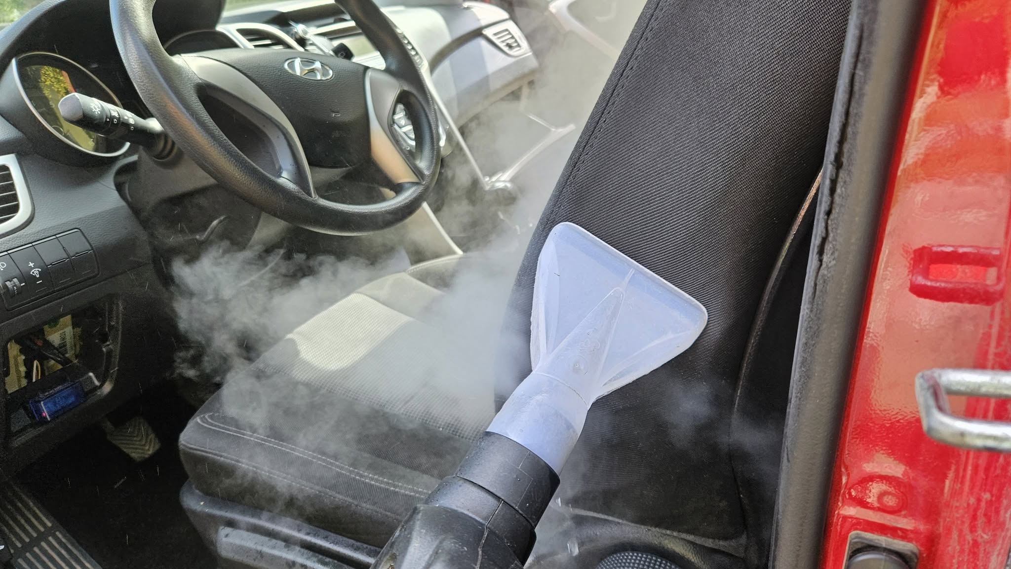 Spălarea profesională a spătarului unui scaun auto textil cu duză de extracție și echipament specializat.